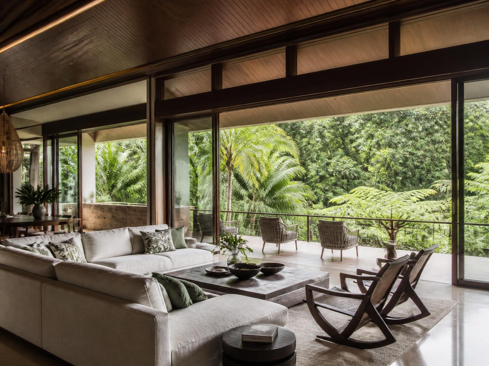 Open-plan villa living room with sliding glass onto rainforest — illustrative image